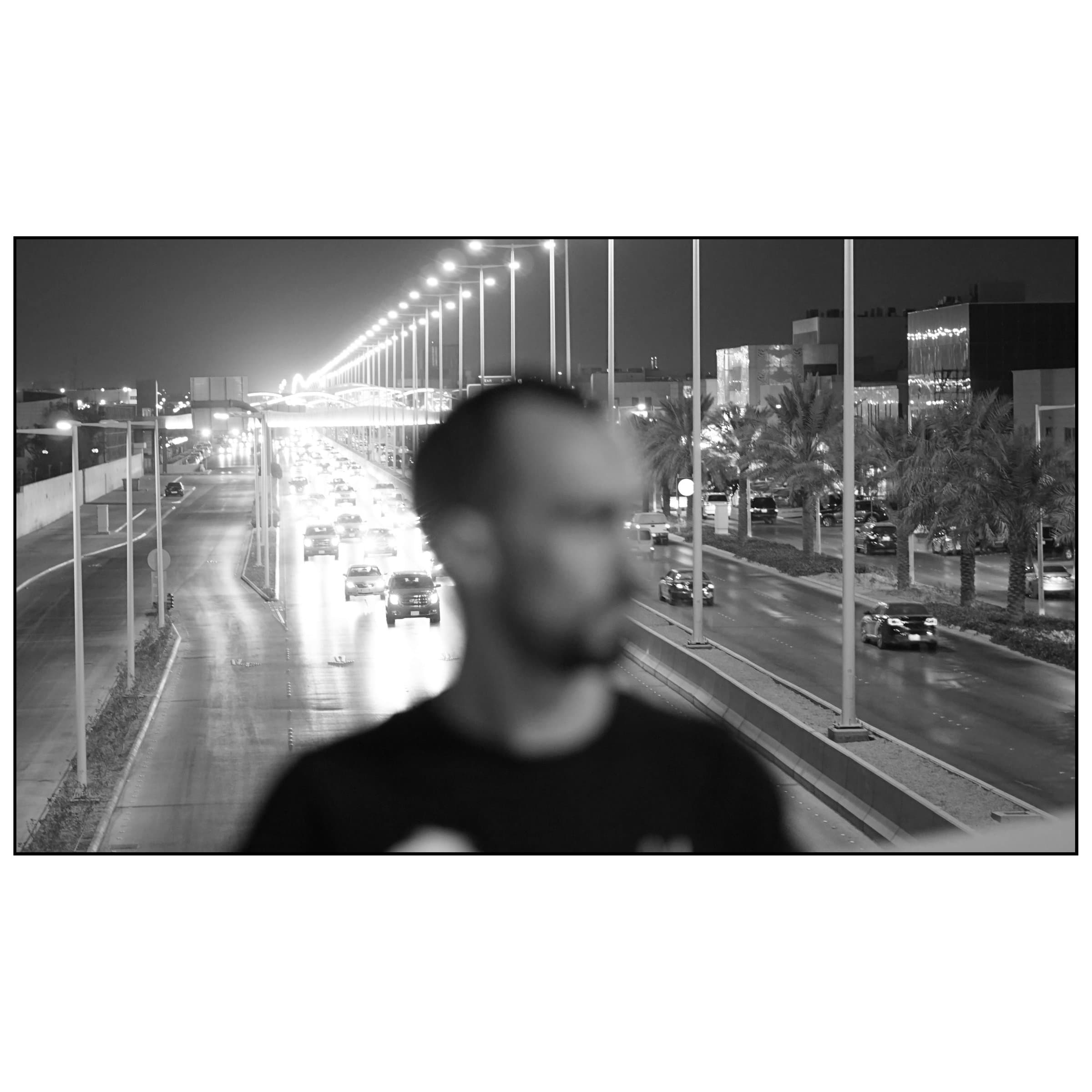 Gece trafiğinin ışıkları önünde odak dışı kalmış adam silueti