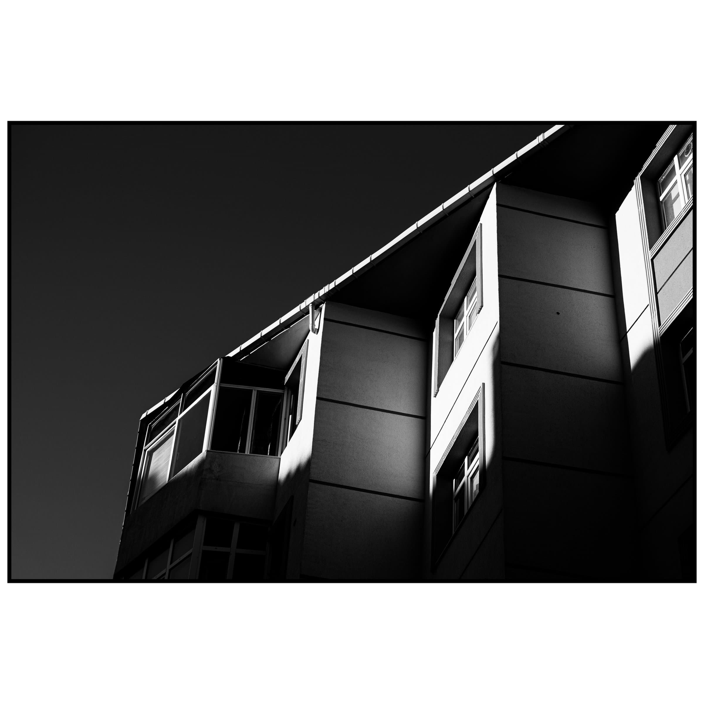 Modern apartman cephesine eğik vuran sert güneş ışığı ve keskin gölgeler
