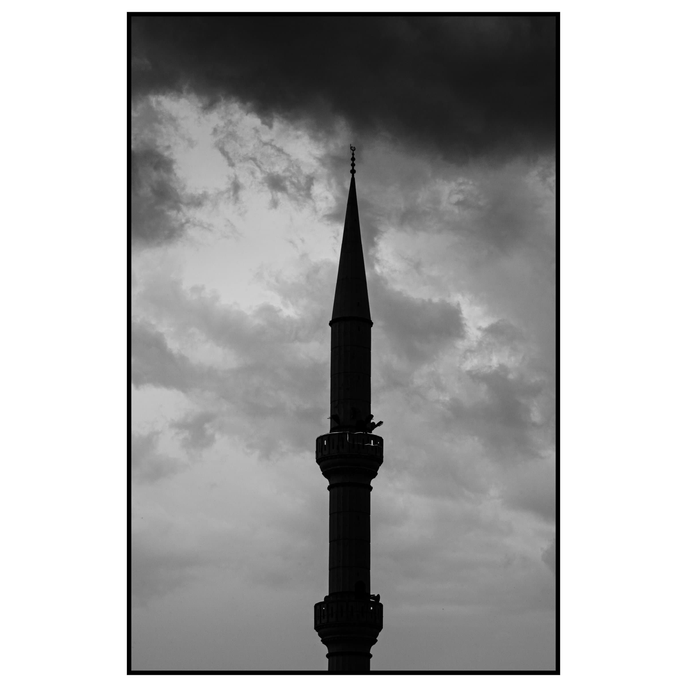 Dramatik koyu bulutların arasından göğe yükselen cami minaresi